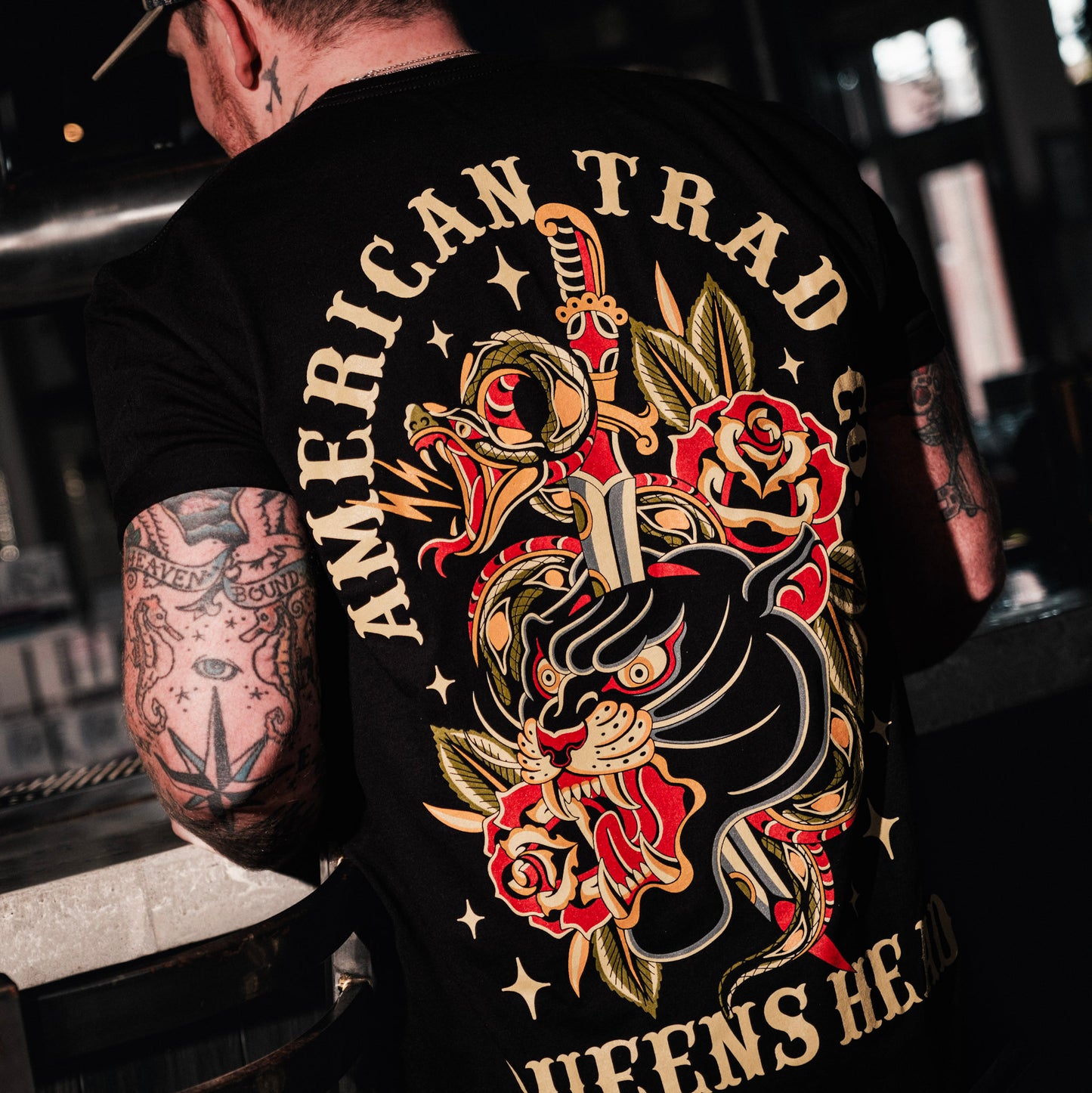 Model wearing Queens Heads First bite tattoo graphic tee, American traditional design in black.