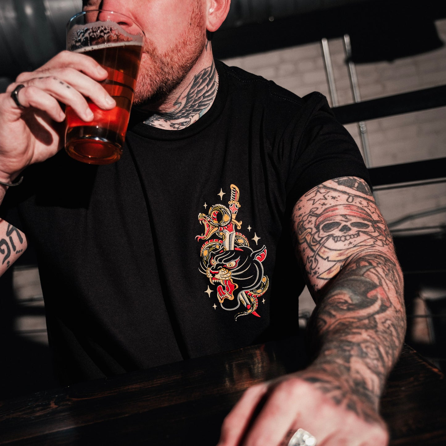 Model wearing Queens Heads First Bite tattoo graphic tee, American traditional design in black.