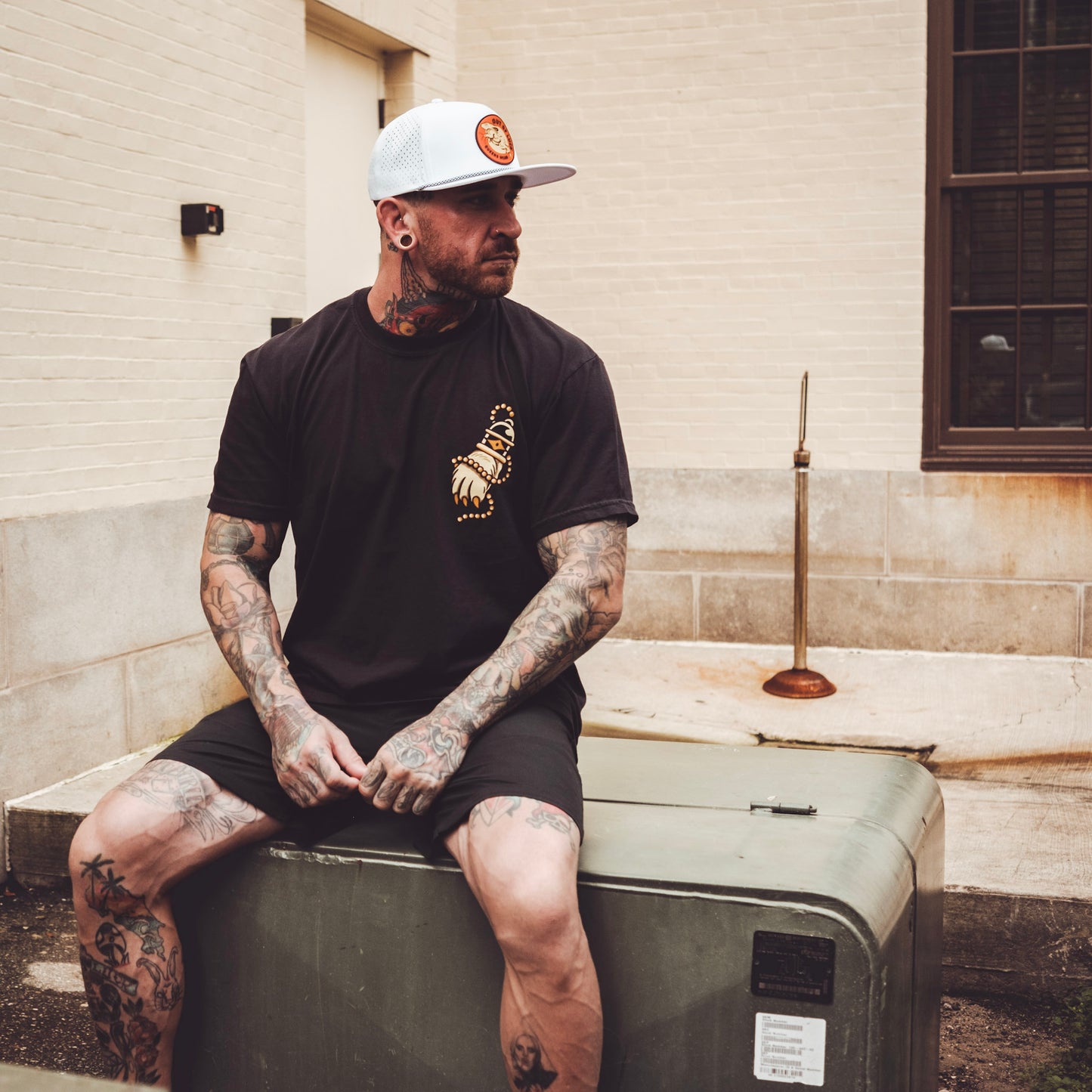 Model sitting wearing Queens Heads Out of Luck tattoo graphic tee, American traditional design in black.